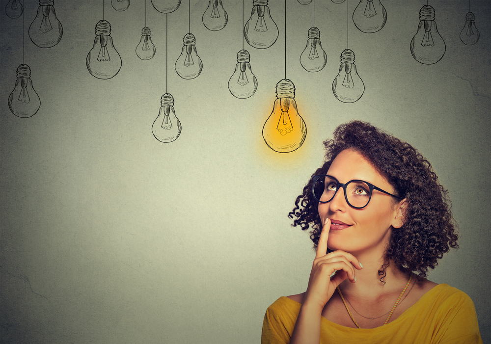 Thinking,Woman,In,Glasses,Looking,Up,With,Light,Idea,Bulb